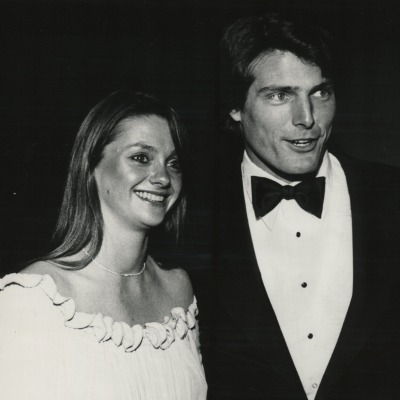 A black and white picture of Christopher Reeve in Tuxedo and smiling Gae Exton beside him.